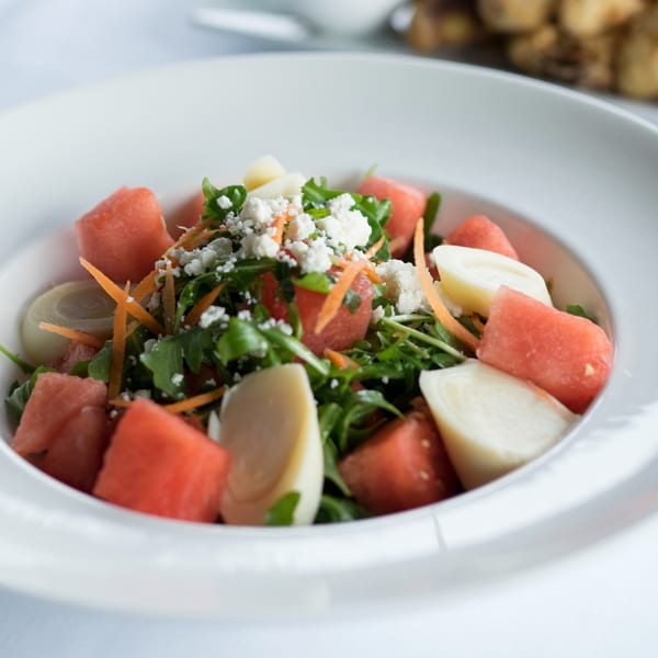 Close-up of a Dolce Restaurant & Wine Bar salad with watermelon, arugula, hearts of palm, and feta.